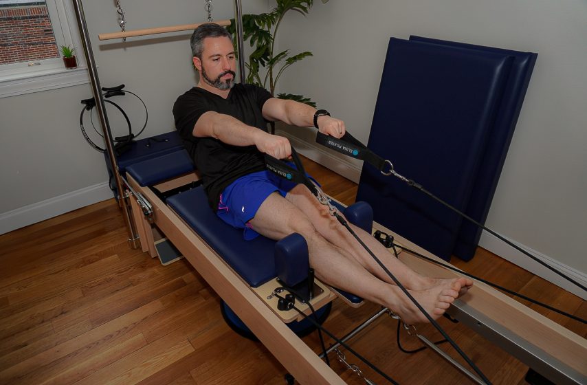 A client training arms with the straps on the reformer